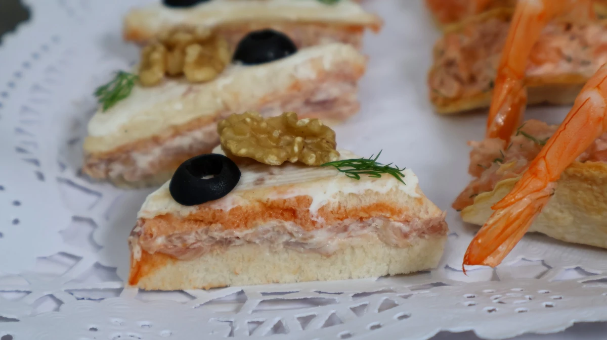 Aperitivo de jamón y queso sobre pan con base de tomate