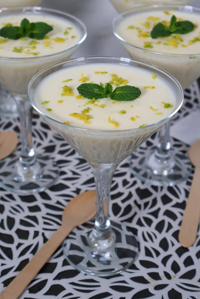 Detalle de lemon posset en copa, crema de limón cremosa decorada con ralladura y menta