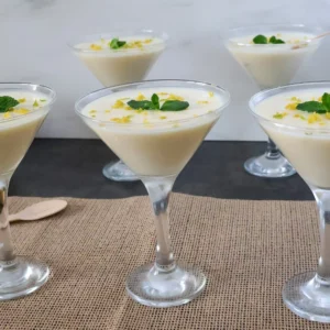 Lemon posset clásico servido en copas, postre británico de limón decorado con ralladura y menta