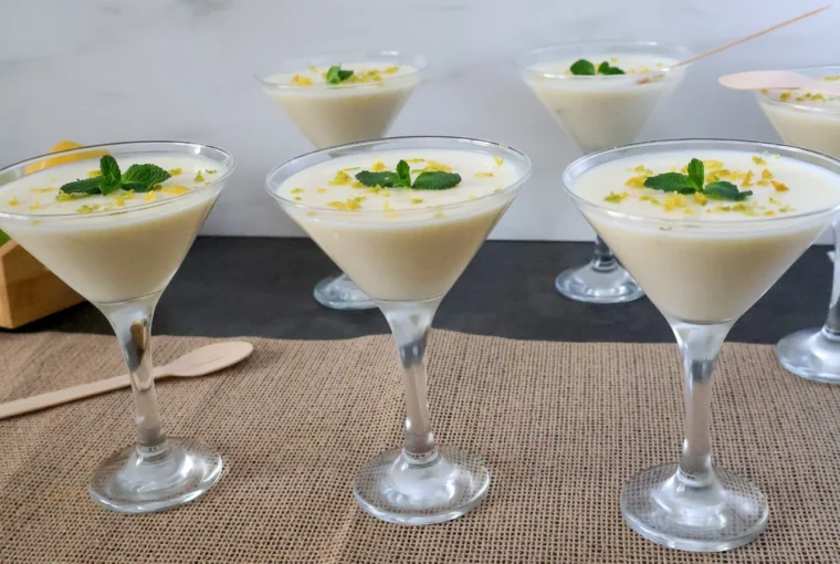 Lemon posset clásico servido en copas, postre británico de limón decorado con ralladura y menta