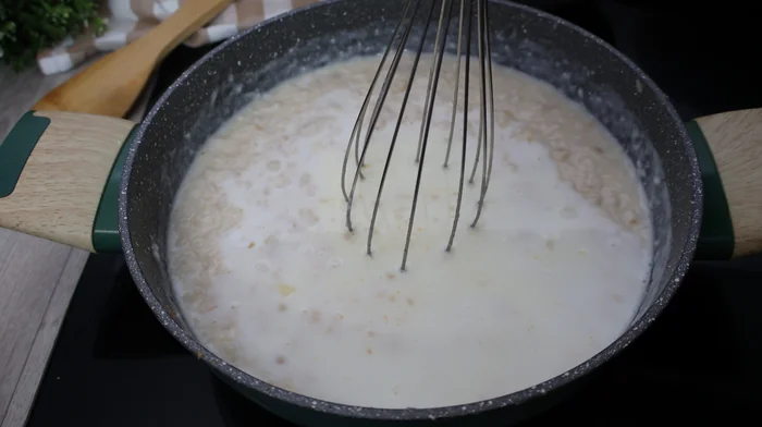 Leche incorporándose a la bechamel con varillas para croquetas