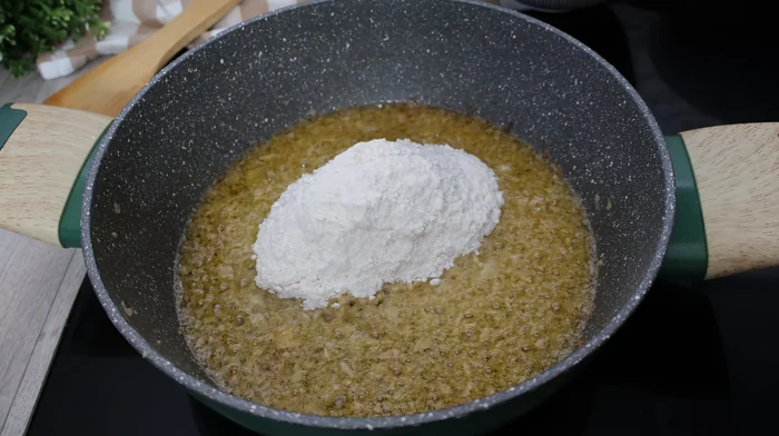 Harina añadida a la mantequilla y el aceite para hacer el roux de las croquetas