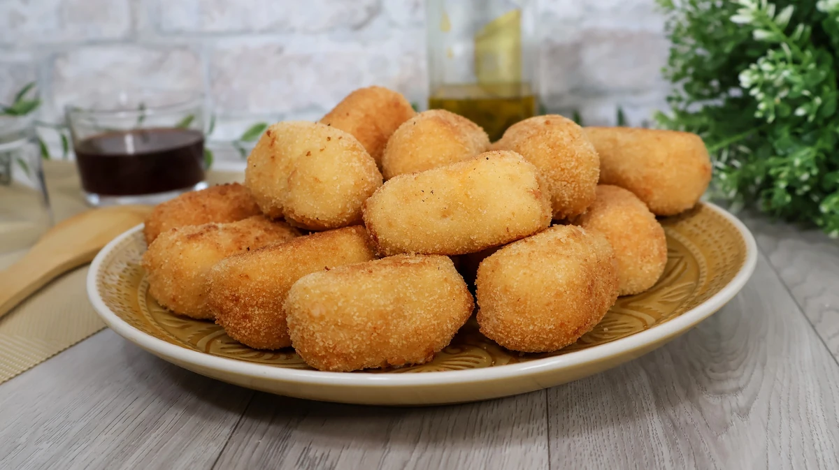 Croquetas tradicionales de merluza y gambas fritas en aceite caliente con rebozado dorado