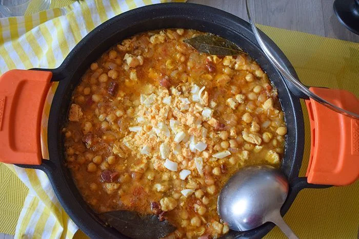 Guiso de garbanzos casero con huevo picado servido en cazuela