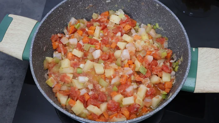 Tomate fresco picado cocinándose en la sopa minestrone italiana