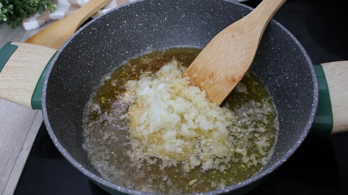 Cebolla picada pochándose lentamente en mantequilla y aceite para croquetas caseras
