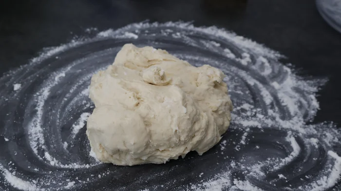 Masa casera de pizza sin formar, sobre superficie enharinada
