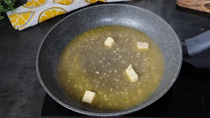 Añadiendo dados de mantequilla para montar la salsa de limón del salmón en salsa