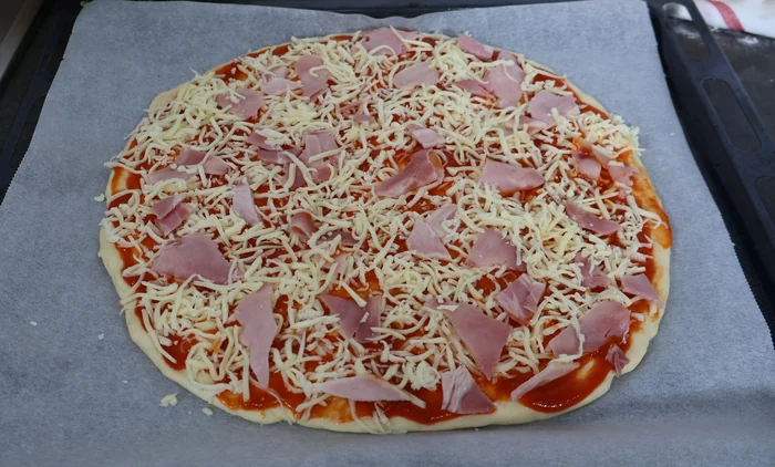 Pizza casera con jamón y queso antes del horneado