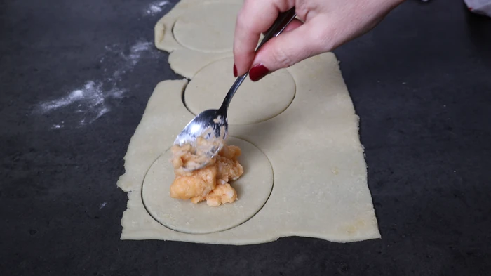 Poniendo el relleno de bechamel de gambas en el centro de los círculos de masa escaldada para formar los rissóis portugueses