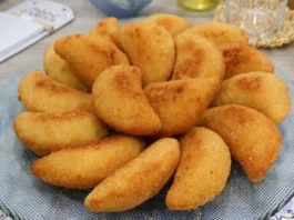 Bandeja de rissóis portugueses de gambas recién fritos, dorados y crujientes, servidos sobre mantel con motivo de azulejos portugueses