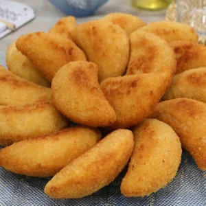 Bandeja de rissóis portugueses de gambas recién fritos, dorados y crujientes, servidos sobre mantel con motivo de azulejos portugueses