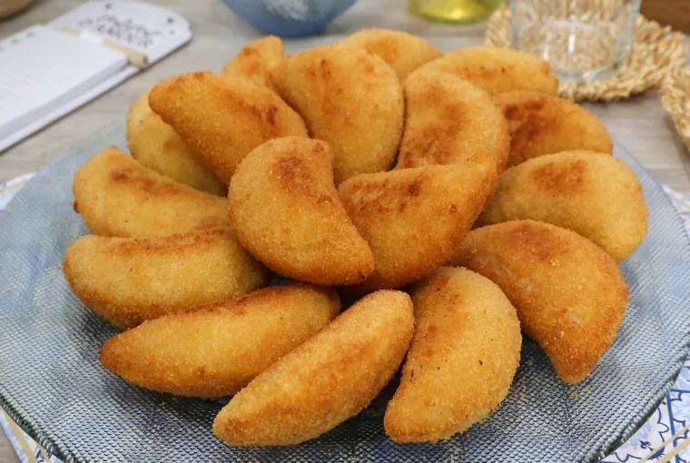 Bandeja de rissóis portugueses de gambas recién fritos, dorados y crujientes, servidos sobre mantel con motivo de azulejos portugueses