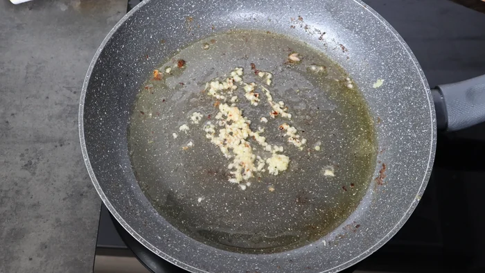 Ajo picado sofriéndose en la sartén para la salsa de limón del salmón en salsa