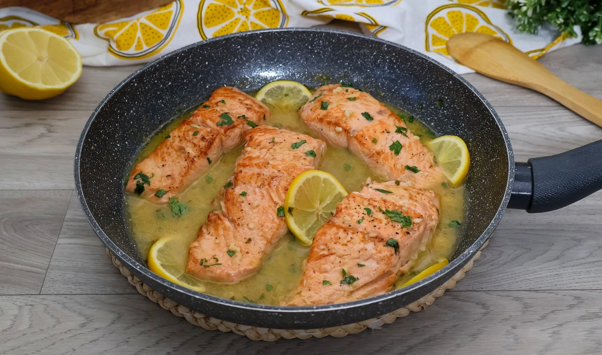 Sartén con salmón en salsa de limón y mantequilla, dorado por fuera y jugoso por dentro
