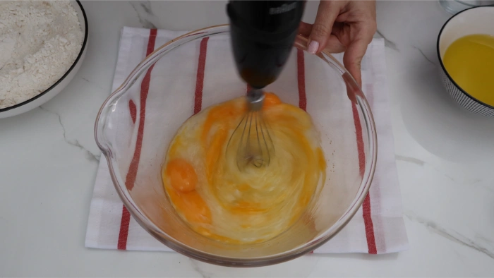 Batiendo huevos y azúcar en bol para bizcocho casero de aceite