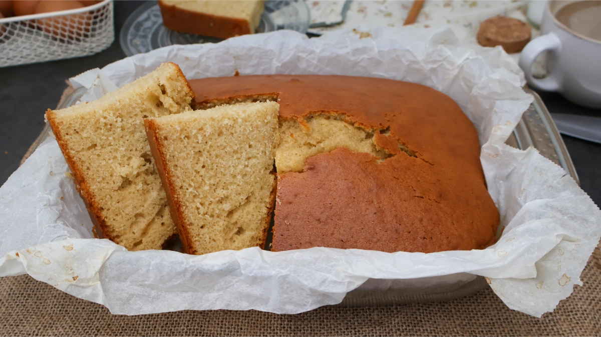 Bizcocho de aceite casero en molde rectangular con rebanadas cortadas y taza de café al fondo
