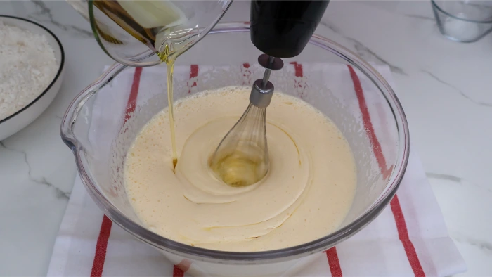Aceite en hilo fino sobre mezcla de huevos blanqueada para bizcocho casero de aceite