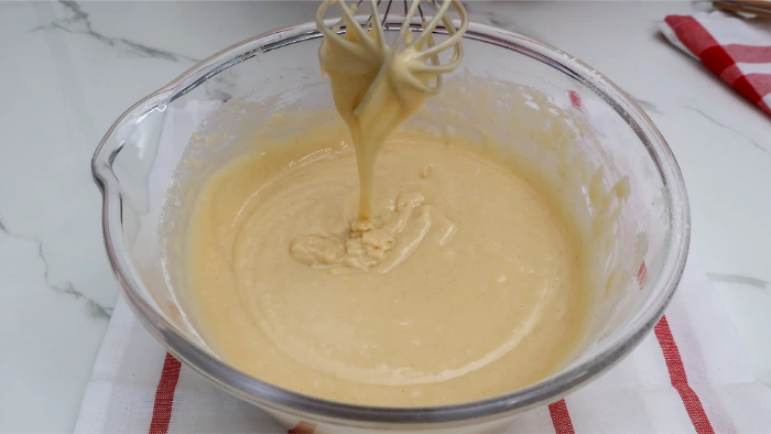 Masa de bizcocho de aceite cayendo en lazo desde las varillas