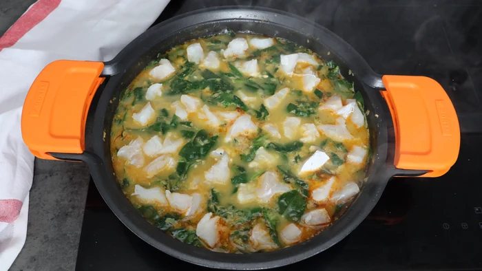 Trozos de bacalao desalado añadidos al potaje de vigilia con garbanzos y espinacas en la cazuela