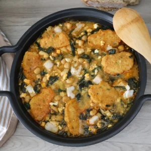 Potaje de vigilia con garbanzos espinacas bacalao y rellenos crujientes en cazuela vista cenital con cuchara de madera