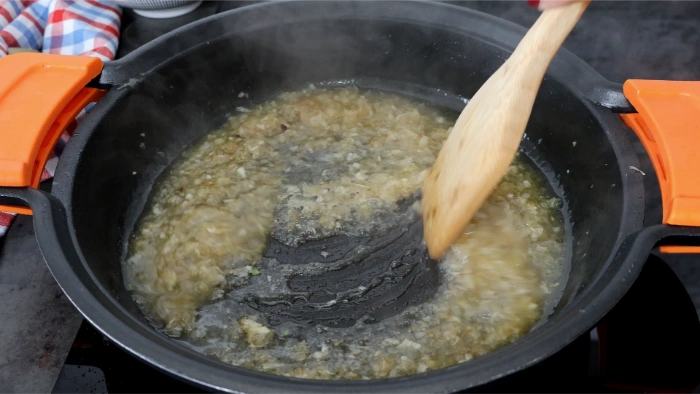 Desglasando el fondo de la cazuela con vino blanco sobre el sofrito de cebolla y ajo, con cuchara de madera