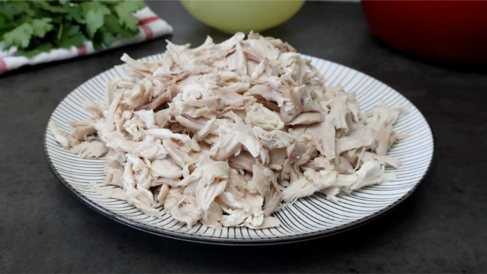 Pollo cocido deshilachado a mano en hebras irregulares sobre plato para el relleno de la kotopita griega
