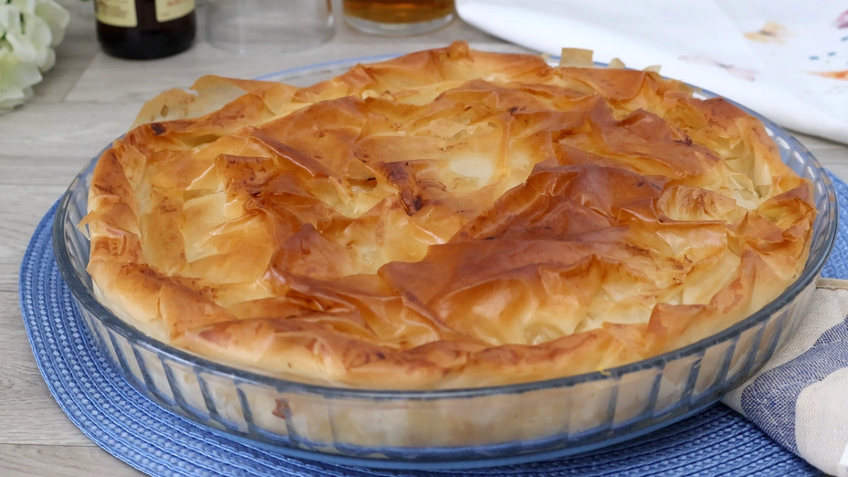 Kotopita griega recién sacada del horno con la masa filo dorada y crujiente en fuente redonda de cristal
