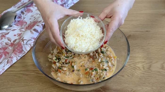 Añadiendo queso rallado gruyère y queso tierno al relleno frío de la kotopita con huevo batido
