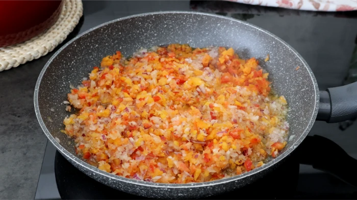 Sofrito de cebolla morada, blanca y pimientos rojo y amarillo pochados en sartén para el relleno de kotopita