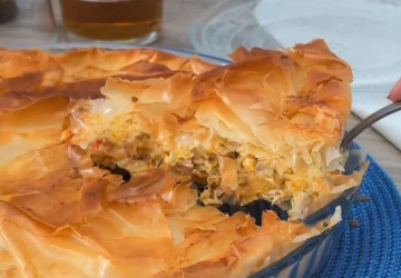 Pastel de pollo griego kotopita con masa filo crujiente y porción levantada mostrando el relleno de pollo, queso y verduras