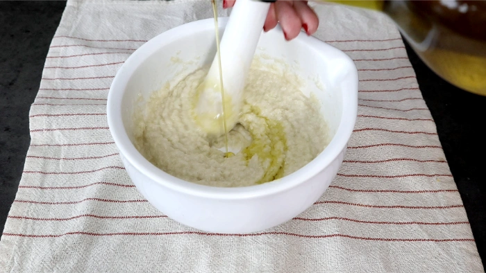 Bol blanco con miga de pan incorporada a la emulsión de ajo, aceite añadiéndose en hilo para terminar el aliño del cojondongo extremeño