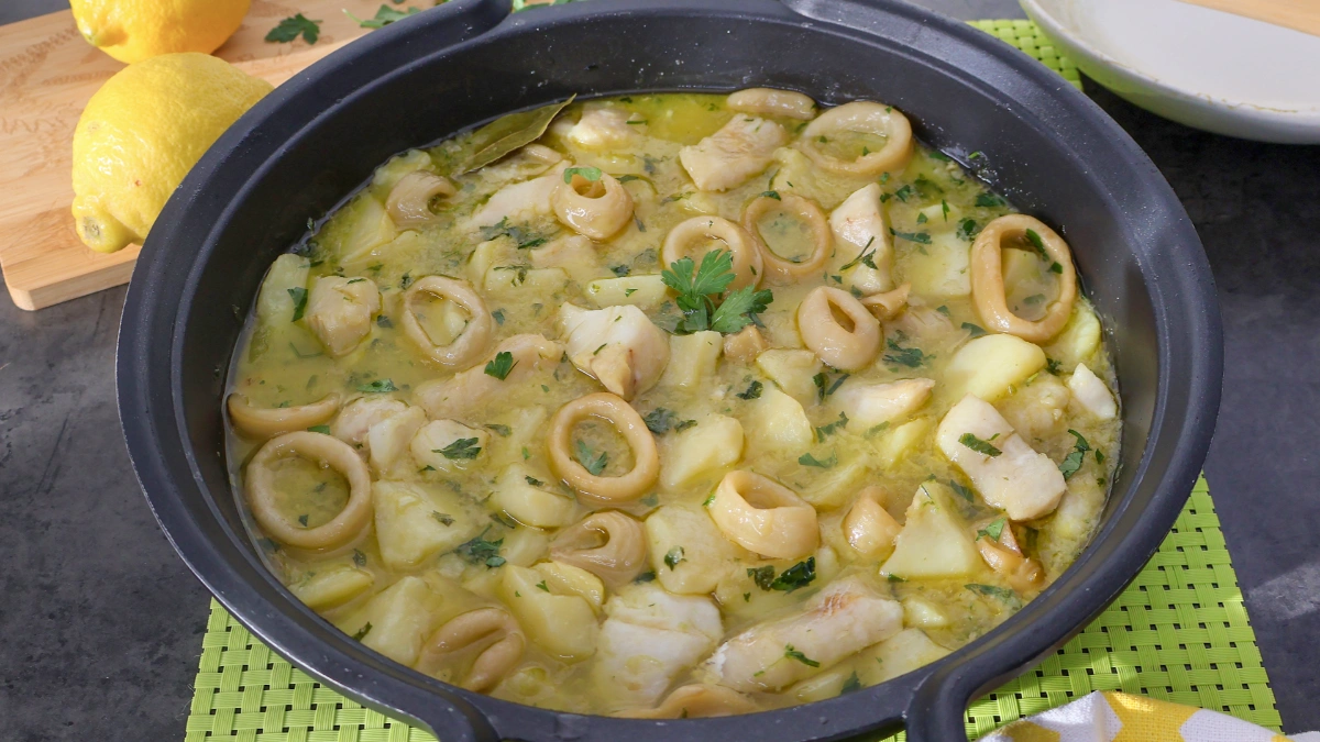 Guiso de merluza y calamares con patatas en salsa verde en cazuela negra
