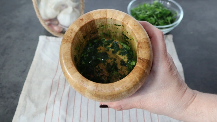 Mortero de madera con majado verde de perejil y ajo