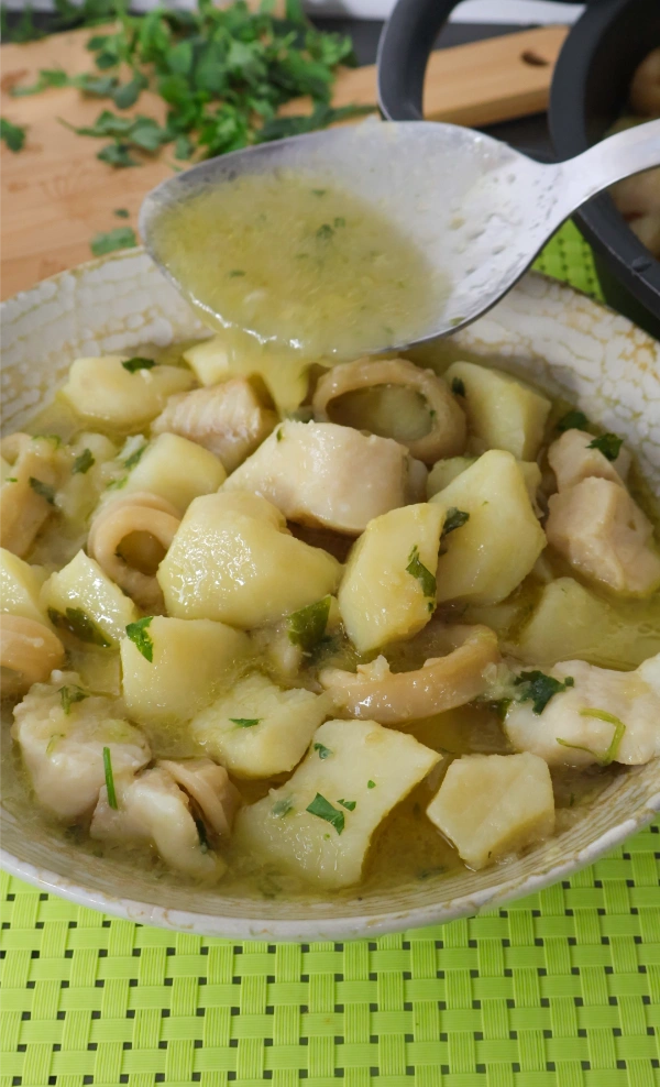 Plato individual de merluza y calamares con patatas en salsa verde con cuchara