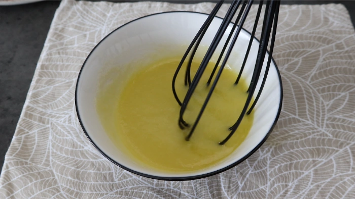 Vinagreta de piña batida con varillas en un bol para aliñar la ensalada de arroz