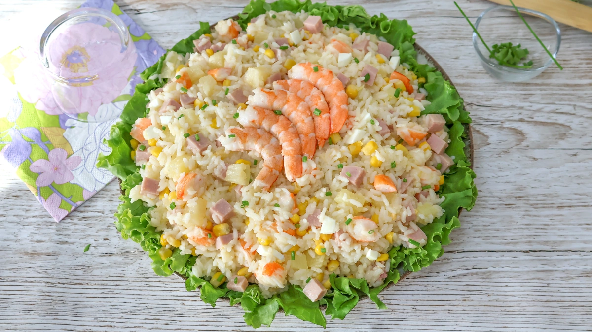 Ensalada de arroz con langostinos, jamón de york, piña, maíz y huevo sobre cama de lechuga