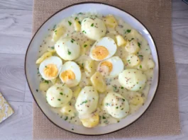 Vista cenital de una fuente de huevos en salsa de mostaza con patatas y perejil picado