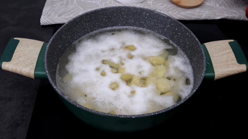 Patatas hirviendo en una cazuela con espuma en la superficie durante la cocción