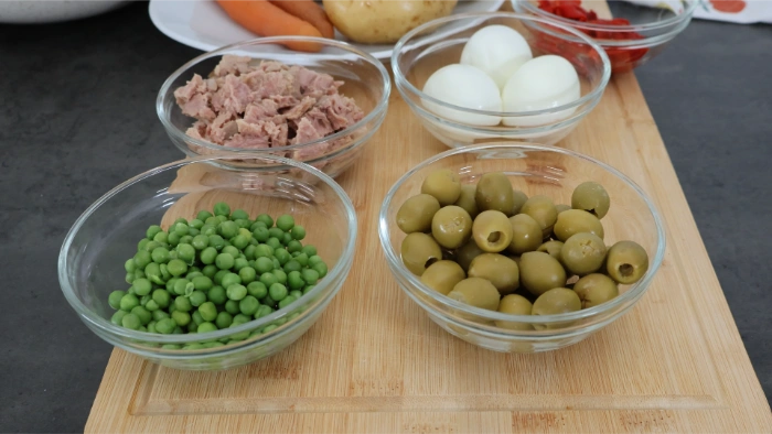 Cuencos con atún escurrido, huevo cocido, guisantes y aceitunas verdes, ingredientes de la ensaladilla rusa