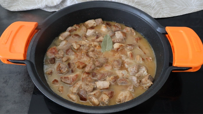 Cazuela con carne dorada y caldo ce carne, lista para la cocción del guiso