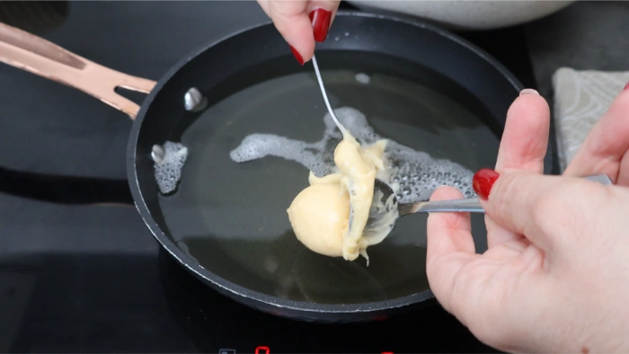 Bolitas de masa de buñuelos friéndose en aceite caliente
