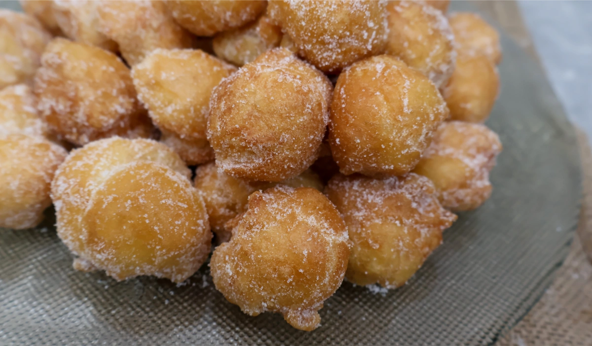 Primer plano de buñuelos de viento dorados y rebozados en azúcar