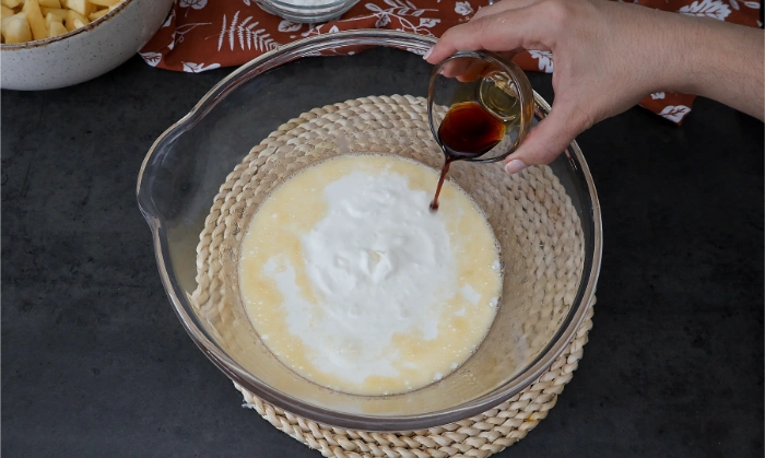 Añadiendo leche, na ta y aroma de vainilla a la mezcla de huevos y azúcar