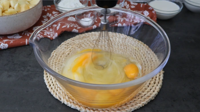 Mezclando huevos y azúcar para preparar la masa de la tarta de manzana